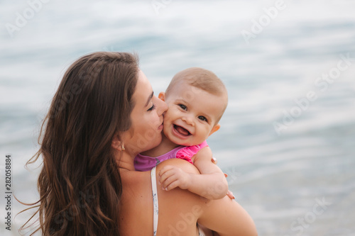 Mom kiss her little daughter on the beach. Backgound of sea © Aleksandr