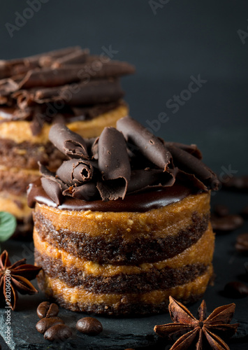 Chocolate cakes on black slatter board with mint, coffee beans on dark background, closeup photo. Fresh, tasty dessert food concept. photo