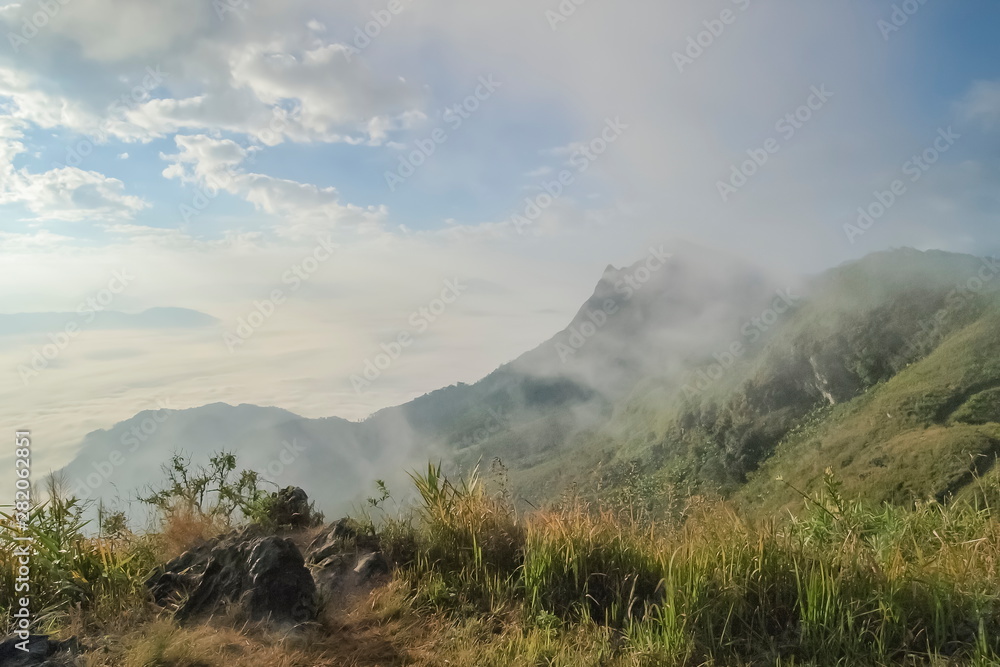 Mountain view misty morning of peak mountain around with soft fog with cloudy sky background, sunrise at Pha Tang, Chiang Rai, northern of Thailand.