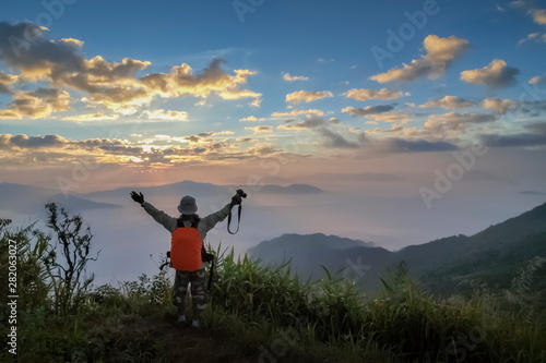 Silhouette a Photographer standing on top hill around with sea of fog and cloudy sky background, sunrise at Pha Tang, Chiang Rai, northern of Thailand.