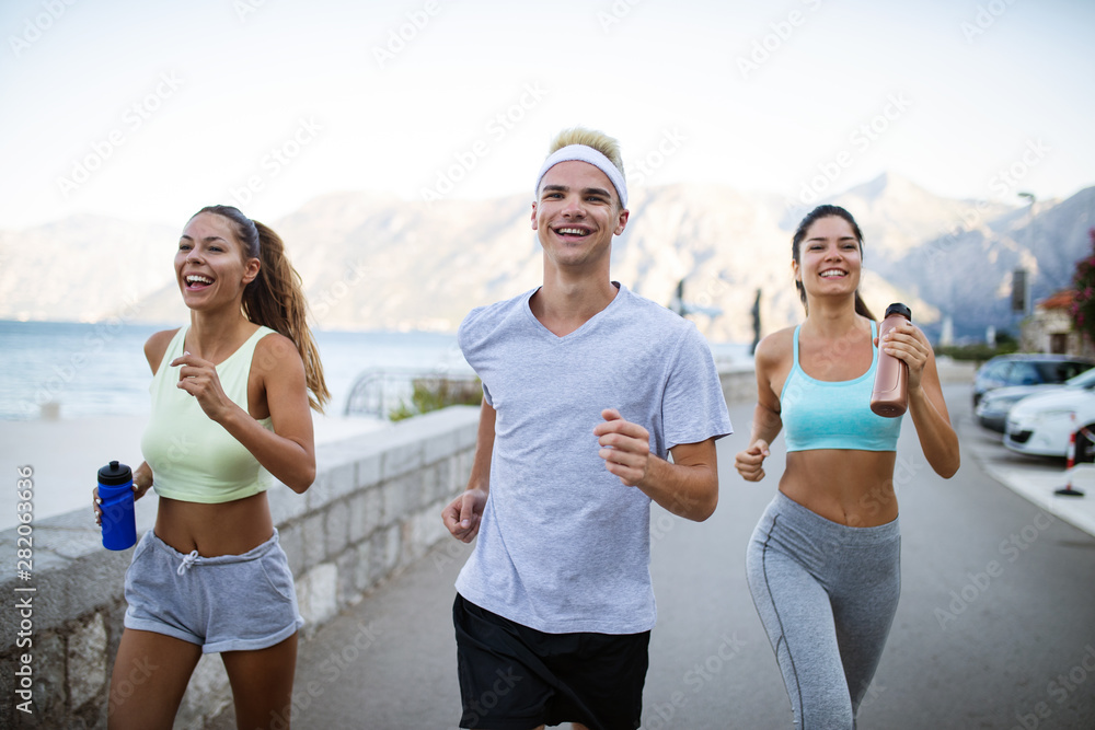 Group of young people friends running outdoors at seaside