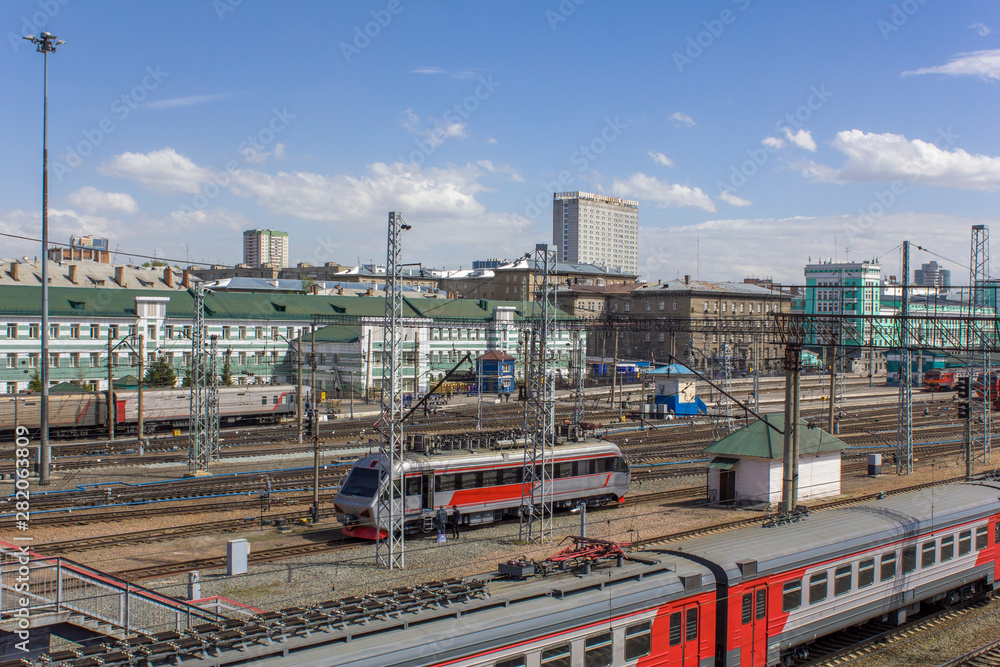 Fototapeta premium railway station with a many rail tracks and modern trains and cars on the background of the city, aerial view