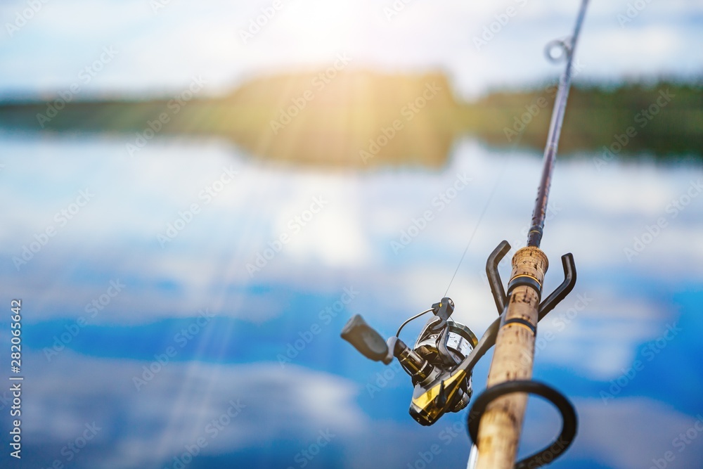 Fishing rod close-up with a beautiful sunrise on blue lake in Finland Fishing rod close-up with a beautiful sunrise on blue lake in Finland