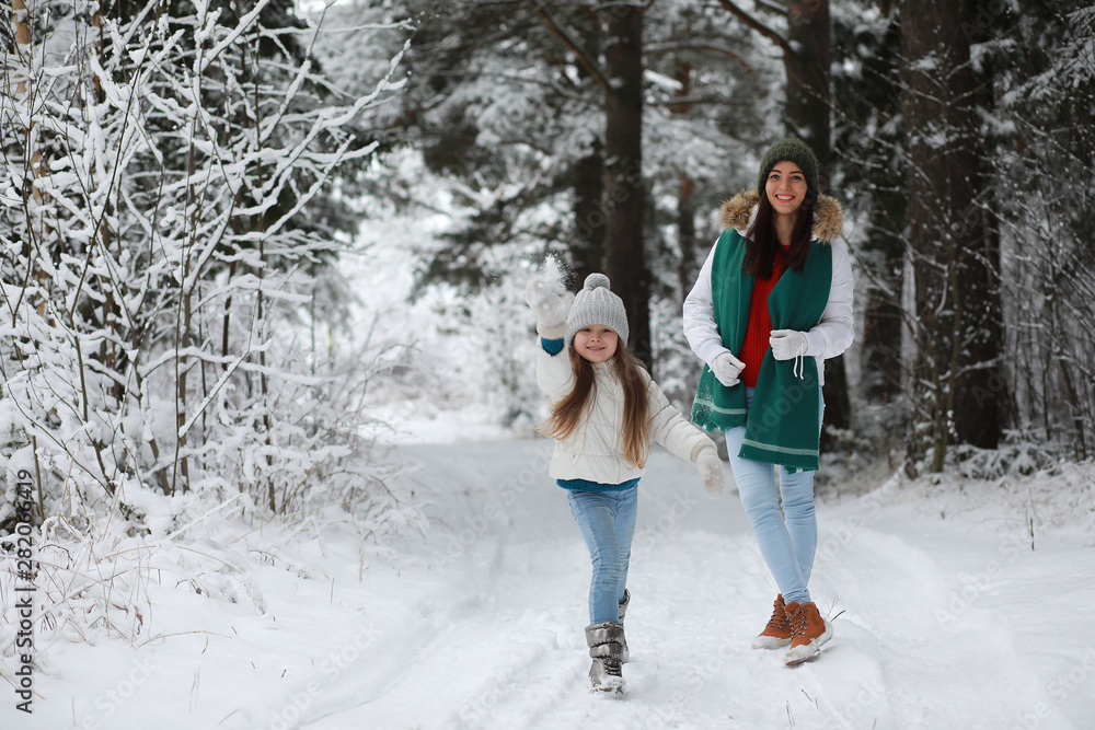 Young family for a walk. Mom and daughter are walking in a winter park.