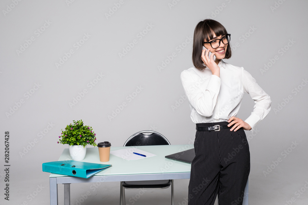 Portrait of happy businesswoman using her mobile phone and making a call while standing in the office. Portrait of happy businesswoman using her mobile phone and making a call while standing in the office.
