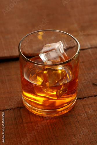 Chilled Whisky Glass with Ice Cubes on Wooden Table