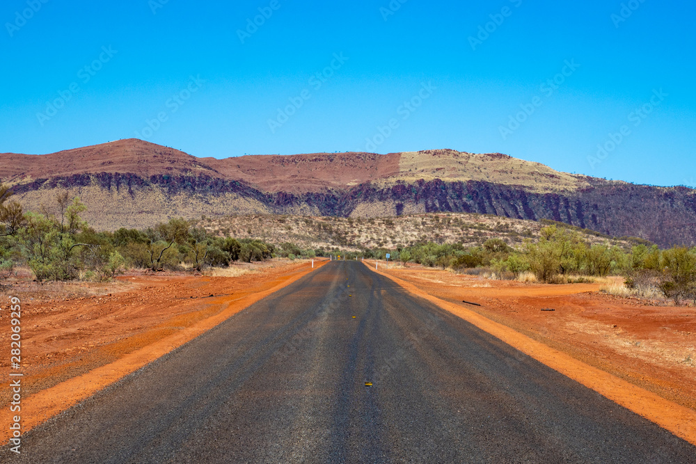 Unmarked freshly paved road leading straight towards mountain wall at Karijini National Park