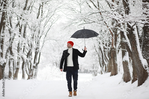 A man on a walk in the park. Young man with in the winter snowfall.