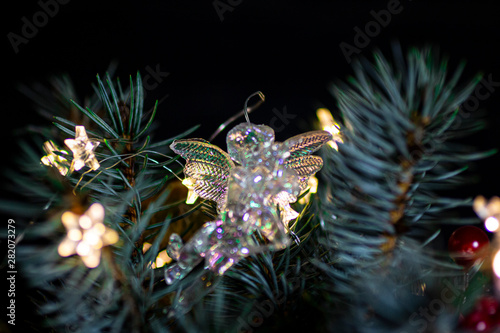 Glass angel on a Christmas tree with a garland in the form of an asterisk.