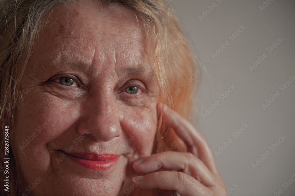 Cheerful elderly woman with red hair smiles and flirts in front of camera Cheerful elderly woman with red hair smiles and flirts in front of camera