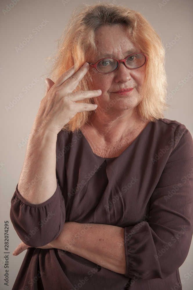 Cheerful elderly woman with red hair in glasses smiles and flirts in front of camera Cheerful elderly woman with red hair in glasses smiles and flirts in front of camera