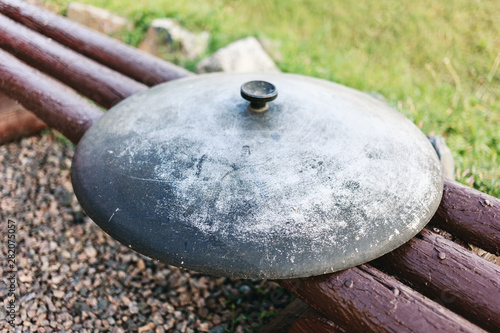 Cauldron lid on a wooden bench. Close-up image of a metal caldron lid.