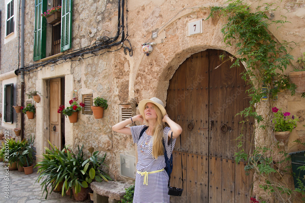 young woman tourist wearing summer hat sightseeing street in mediterranean town in summer season