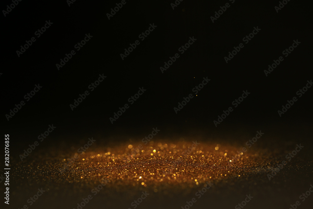 Abstract background of Sprinkle gold dust with glitter lights on black background Abstract background of Sprinkle gold dust with glitter lights on black background