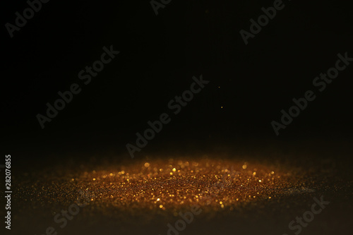 Abstract background of Sprinkle gold dust with glitter lights on black background