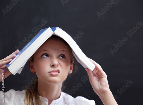 Giovane studente con un libro sopra la testa photo