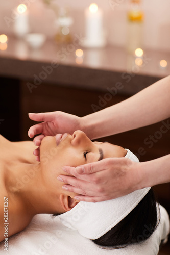 Close up portrait of beautiful mixed-race woman enjoying face massage in luxury spa, copy space
