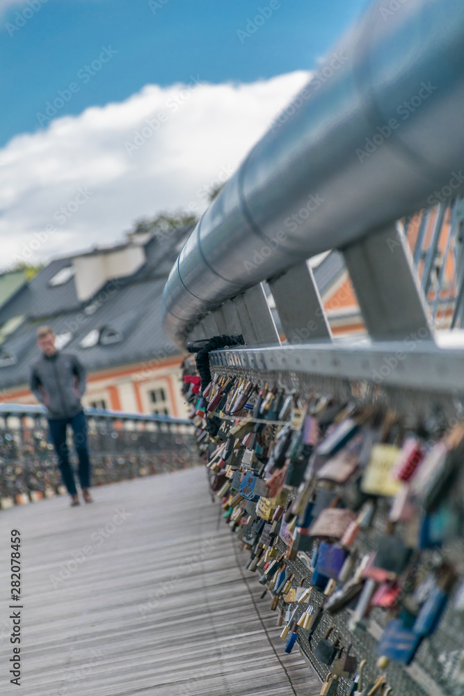 Blurred single man walks near to Romantic Padlocks with the name of couples, attached to a bridge, representing the durability of their eternal love.