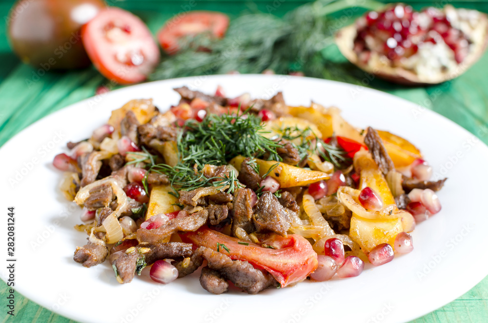 Baked veal with tomatoes decorated with herbs and pomegranate fruits natural color background Baked veal with tomatoes decorated with herbs and pomegranate fruits natural color background
