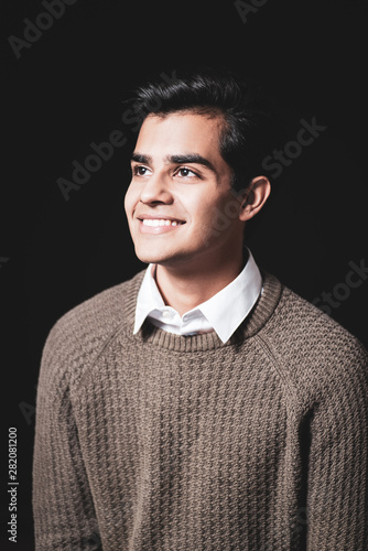 Junger Mann sympathisch lachend vor schwarzem Hintergrund 
