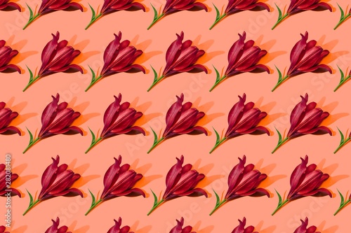 Red lilies on orange background trend flat lay concept with fashionable toning. Many flowers pattern