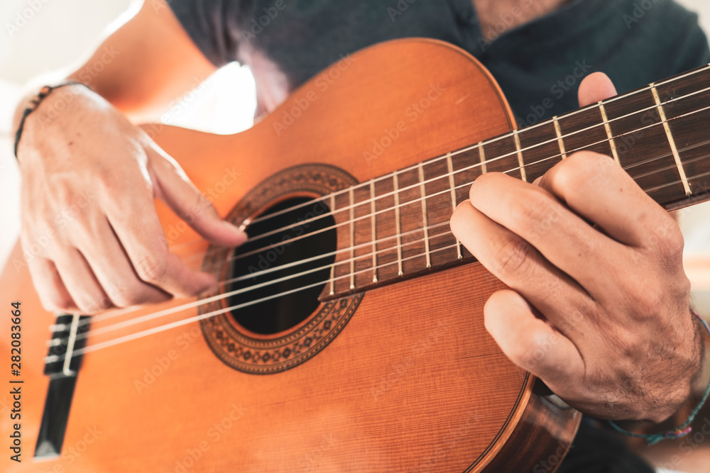 man's hands playing acoustic guitar, close up