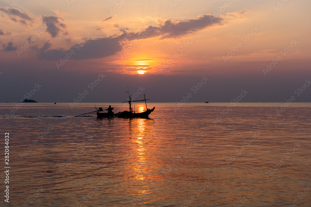 Silhouette of a man on a boat during sunset at sea.
