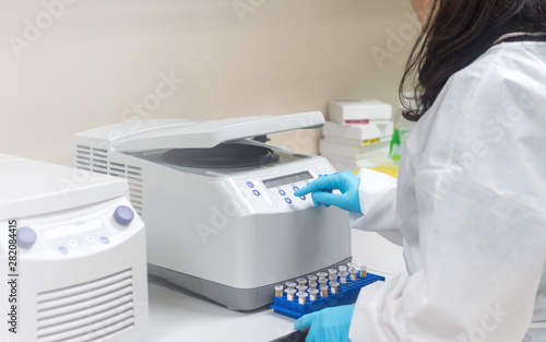 Scientist, worker, Laboratory technician using centrifuge device automation machine for testing and diagnostic clinical specimens sample in lab room of hospital. Medical science technology concept.