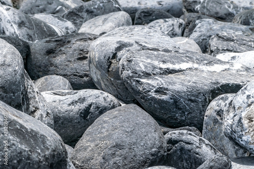 Gray and white large pebbles stone pile background. Natural environmental decorative material. Stone fence or wall