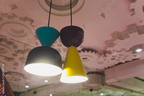 modern chandelier with LED lamps hanging on the ceiling in the interior of the room inside the house, design of home, warm light from shades. photo