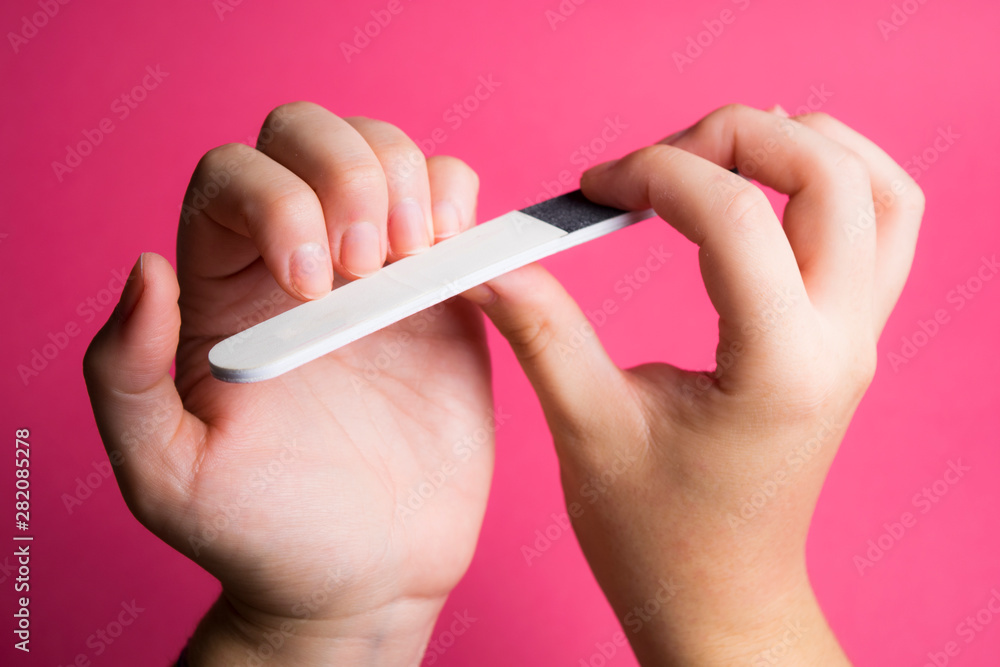 natural hands filing nails on pink background natural hands filing nails on pink background