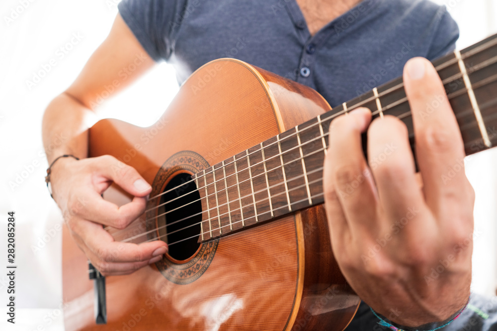 Fototapeta premium man's hands playing acoustic guitar, close up