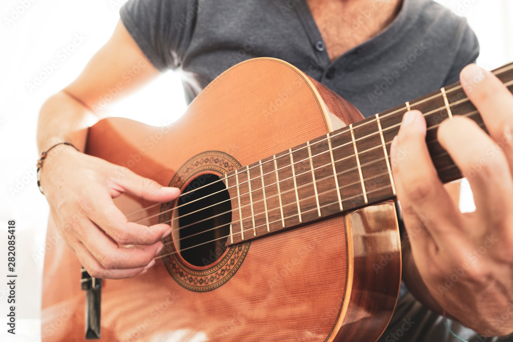 man's hands playing acoustic guitar, close up