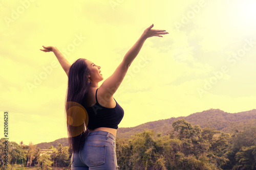 Happy Woman hands up to sky feel freedom confident and independent over sunset sky