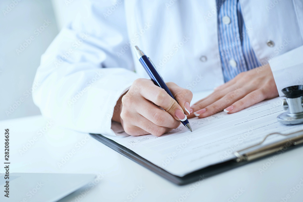 Female medicine doctor hand holding silver pen writing something on clipboard closeup.. Ward round, patient visit check, medical calculation and statistics concept. - obrazy, fototapety, plakaty 