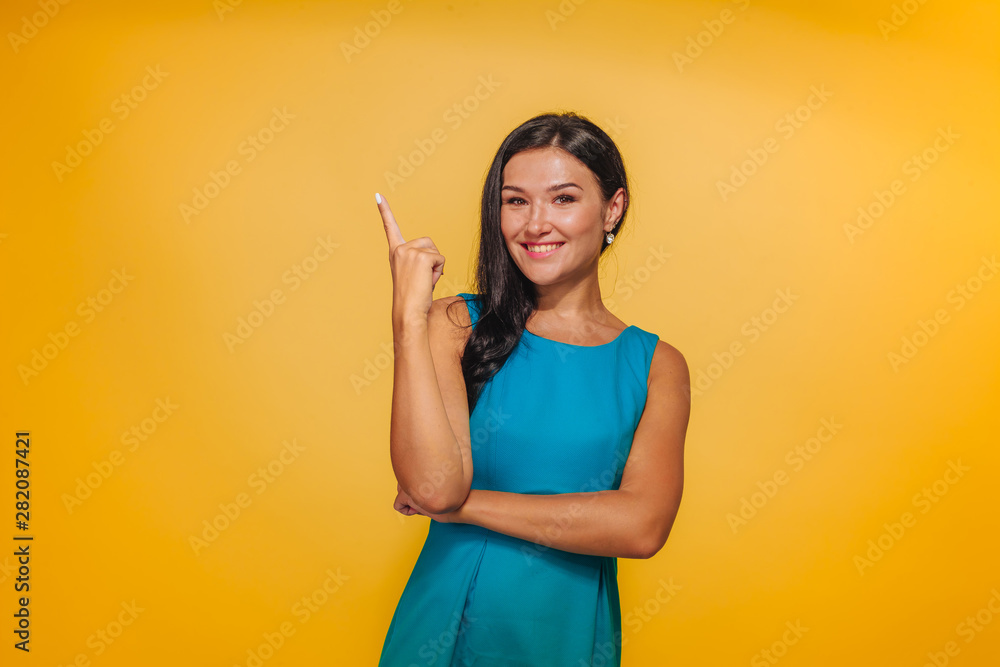 Girl on yellow background pointing finger Girl on yellow background pointing finger