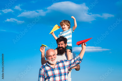 Fathers day - grandfather, father and son are hugging and having fun together. Childhood concept. Male multi generation family.