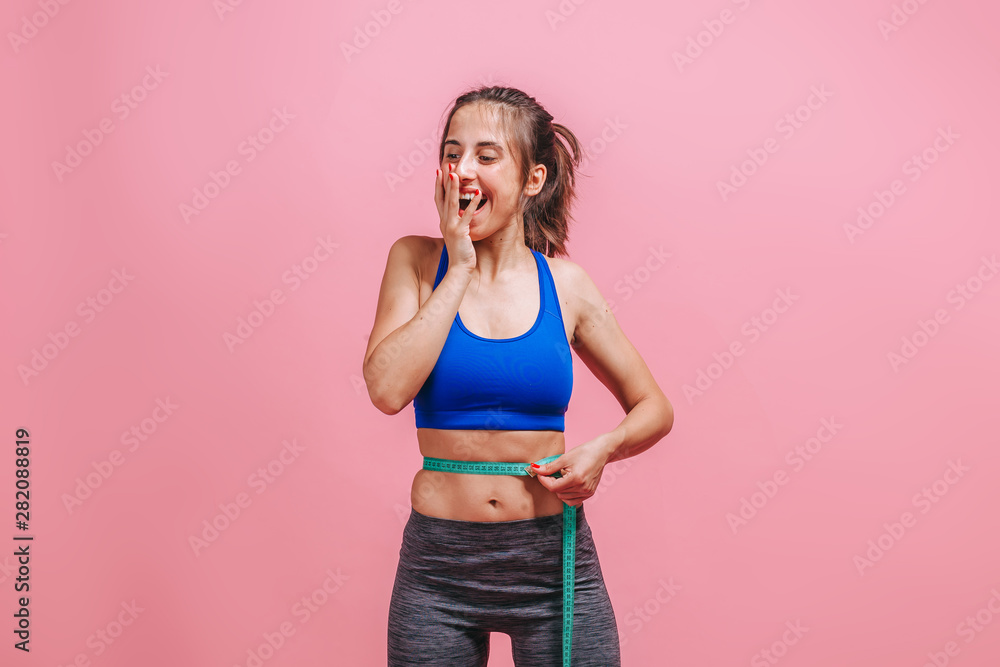 girl measures waist and enjoys on pink background girl measures waist and enjoys on pink background