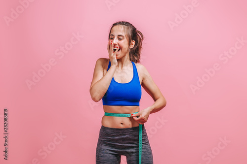 girl measures waist and enjoys on pink background © Smeilov