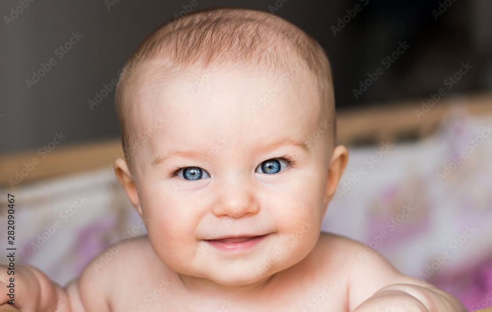 Happy beautiful 6 months old baby with big blue eyes smiling in her crib Happy beautiful 6 months old baby with big blue eyes smiling in her crib