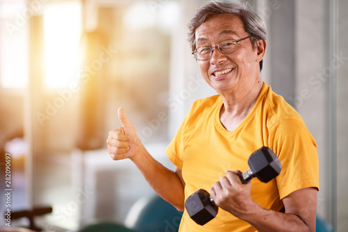 Elderly man lifting dumbbell in the gym