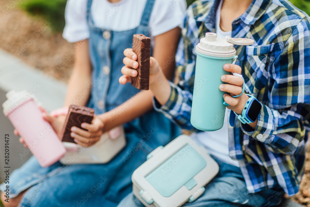 Fototapeta premium Close up photo. Breakfast time for children. Thermos and sweets cake on friends hands.