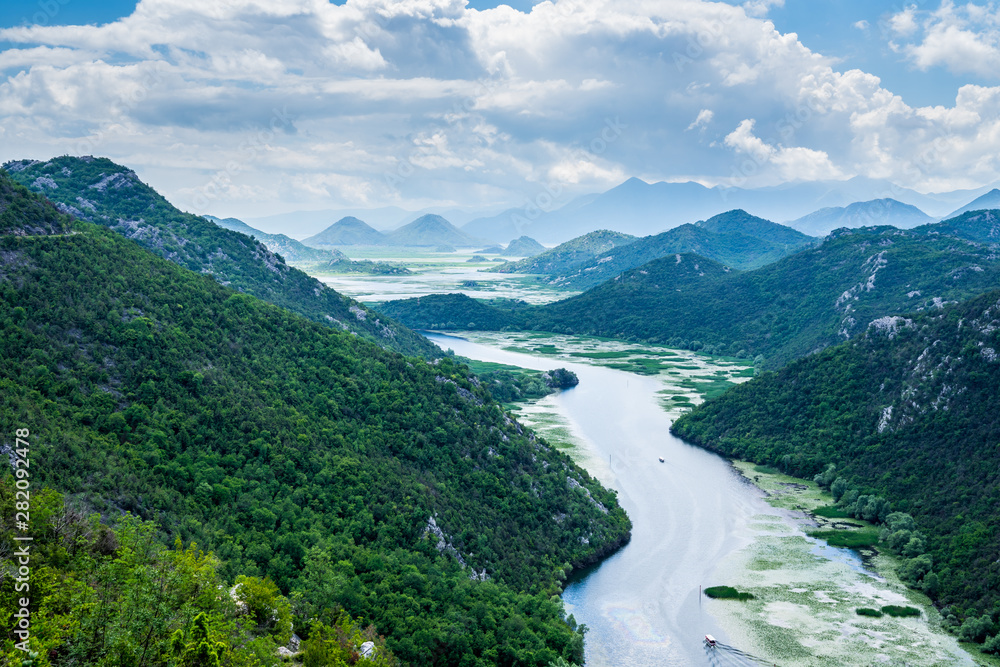 Montenegro, Spectacular green mountains surrounding crnojevica river water with tour boats on it near skadar lake