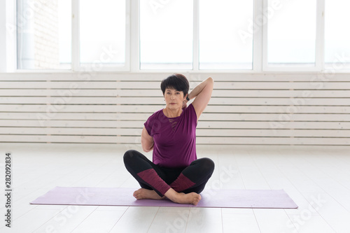 Yoga, people concept - a middle-aged woman doing a yoga in the gym