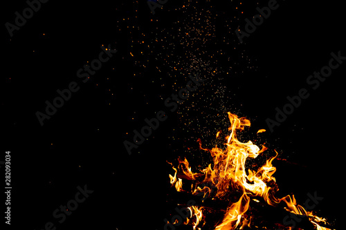 Burning woods with firesparks, flame and smoke. Strange weird odd elemental fiery figures on black background. Coal and ash. Abstract shapes at night. Bonfire outdoor on nature. Strenght of element.