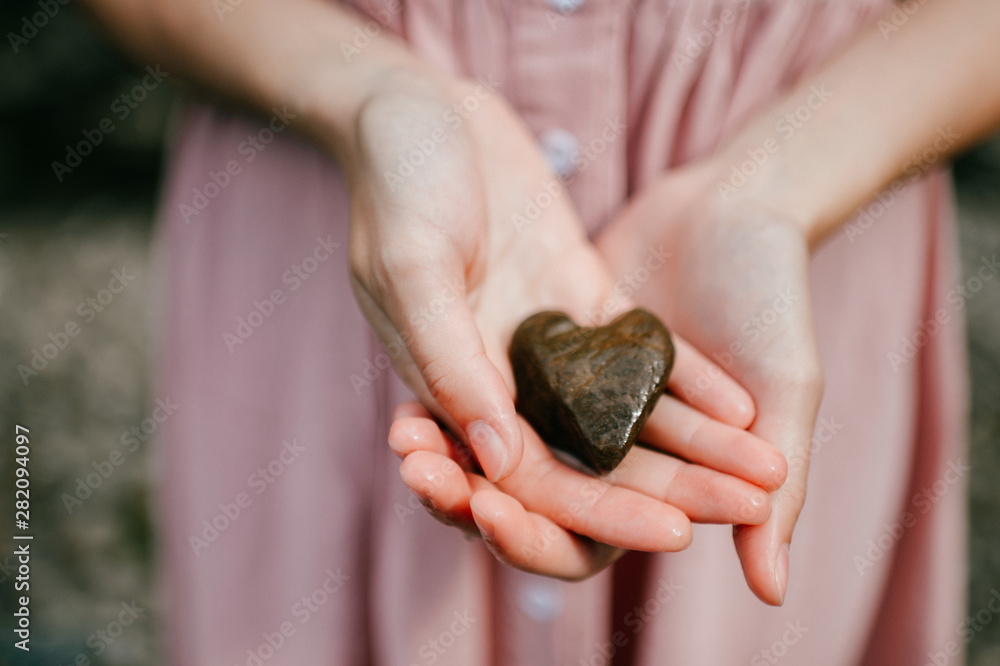 Female hands holding stone looking like heart