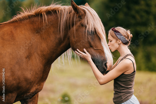 Young beautiful girl hugging horse at nature. Horse lover.