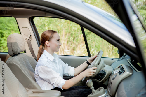 Close up portrait of pleasant looking female with glad positive expression, being satisfied with unforgettable journey by car, sits on driver s seat. People, driving, transport concept