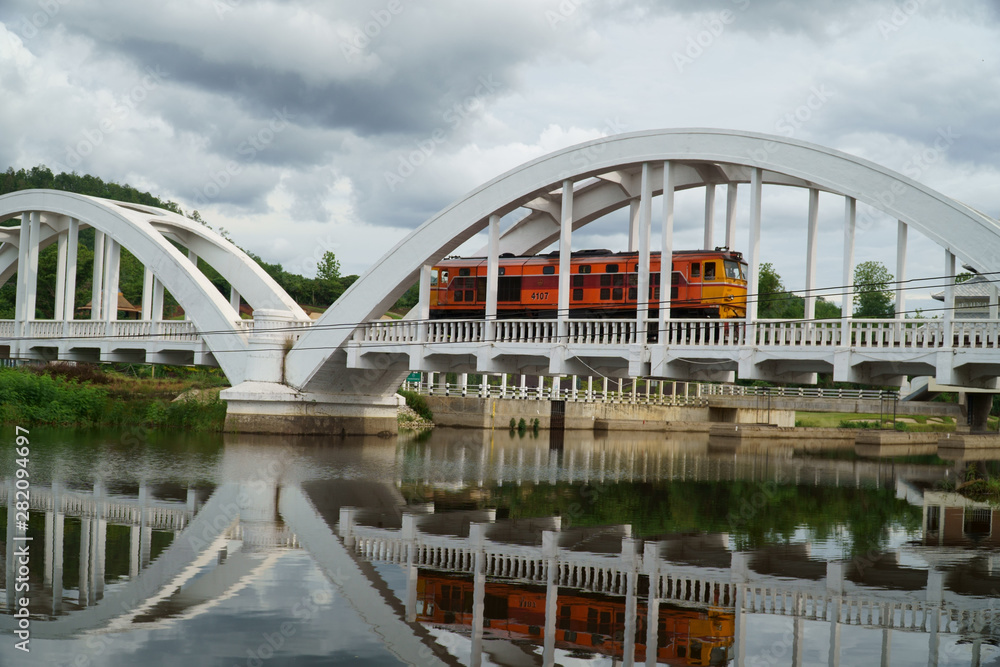 Fototapeta premium Diesel Train passing the Tha Chom Phu railway bridge or white bridge