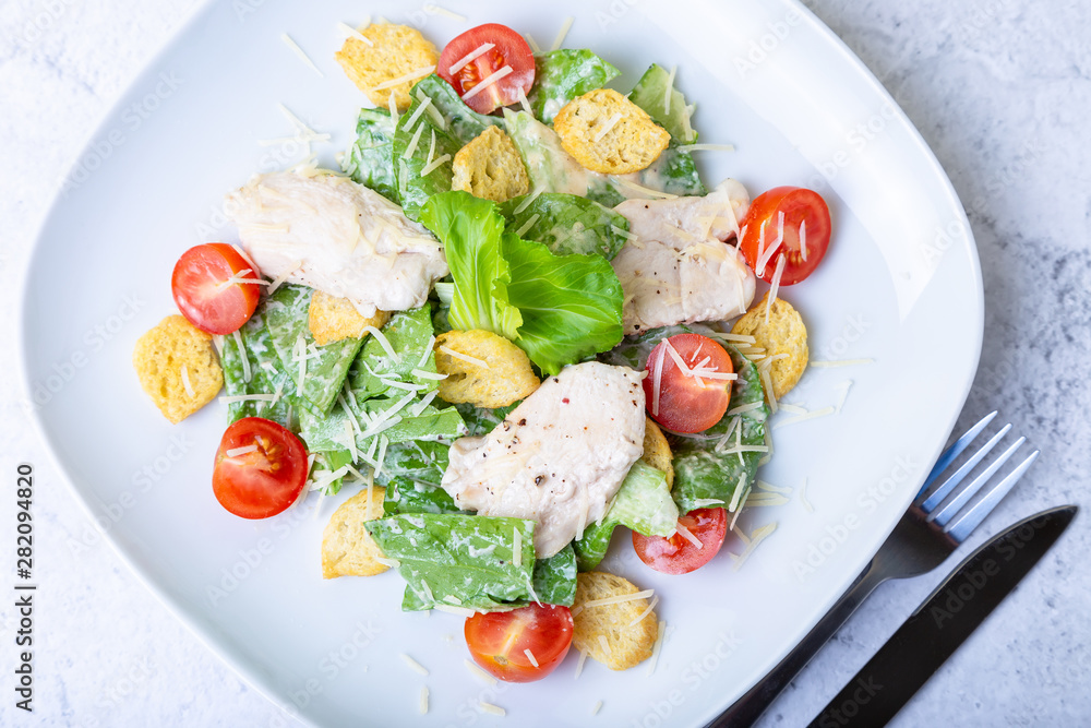 Caesar (cesar) salad with chicken, crackers, parmesan and cherry tomatoes. Close-up. Caesar (cesar) salad with chicken, crackers, parmesan and cherry tomatoes. Close-up.